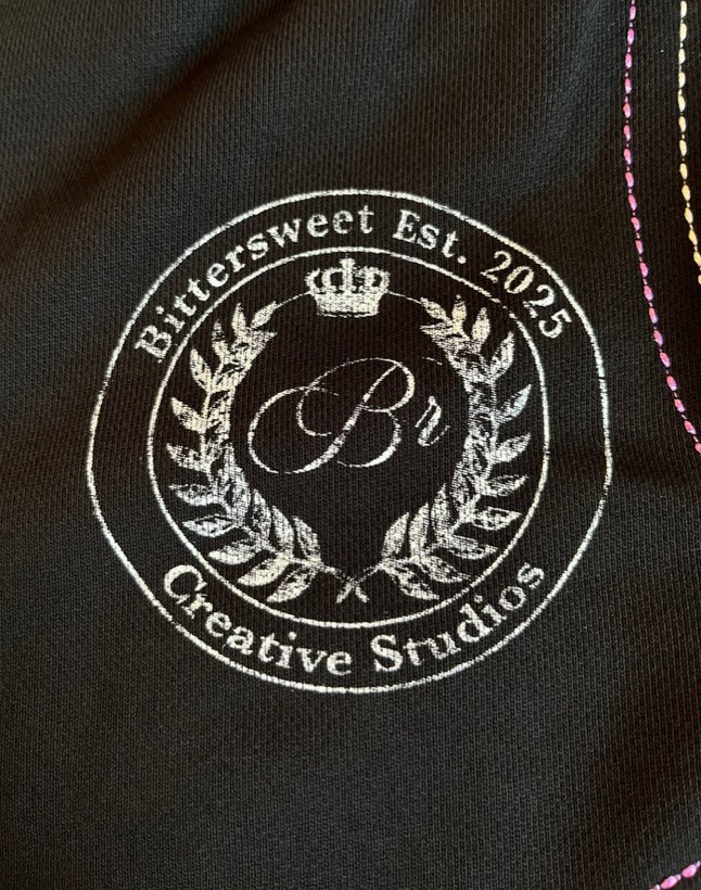 Macro of the embroidered crest: a crown above a script B, framed by laurel, reading Bittersweet Est. 2025 Creative Studios.